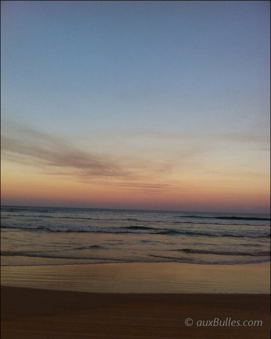 Le coucher de soleil marie le ciel pastel et le sable brun