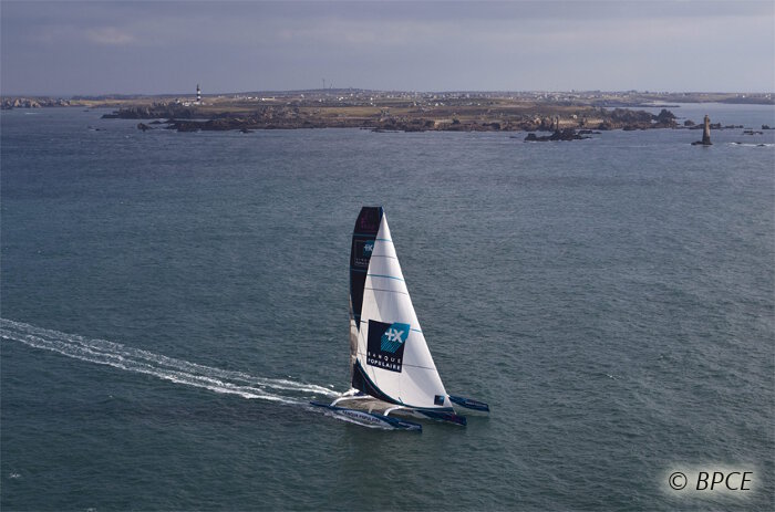 Passage de la ligne de départ du Trophée Jules Verne par Banque Populaire V, le maxi trimaran de Loïck Peyron