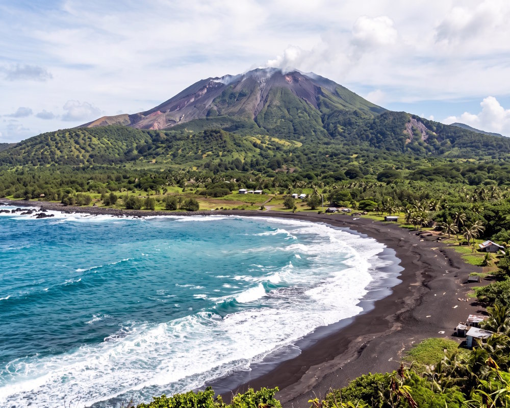 Plage de sable noir avec le volcan Pagan en arrière-plan, sur la côte sauvage de l’île de Pagan, dans les îles Mariannes du Nord