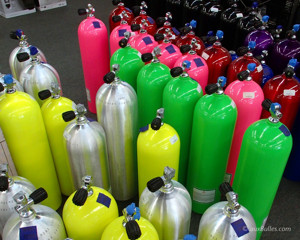 Des bouteilles de plongée aux couleurs fluo en exposition dans un magasin