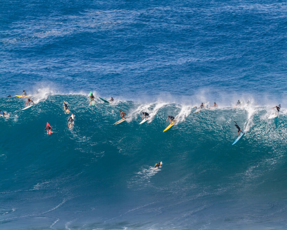 A Waimea bay, sur l'île d'O'ahu, des surfeurs chevauchent une vague géante impressionnante du légendaire North Shore d'Hawaï A Waimea bay, sur l'île d'O'ahu, des surfeurs chevauchent une vague géante impressionnante du légendaire North Shore d'Hawaï