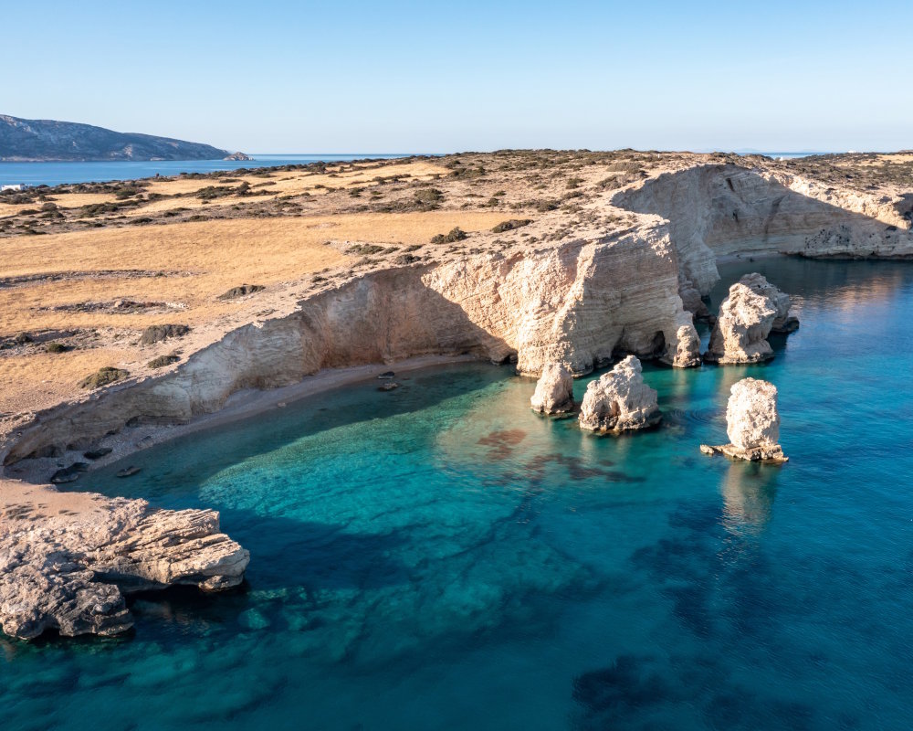 Aerial view of the secluded beaches of Kato Koufonissi, surrounded by rocky cliffs and crystal-clear turquoise waters Aerial view of the secluded beaches of Kato Koufonissi, surrounded by rocky cliffs and crystal-clear turquoise waters