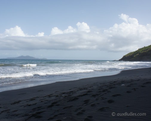 Une plage de sable noir au Sud de Basse-Terre avec les îles des Saintes à l'horizon