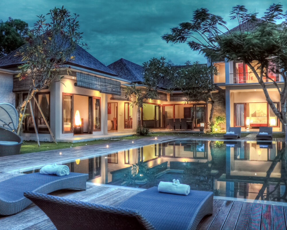 Les reflets nocturnes d'une villa tropicale se dessinent à la surface calme de sa piscine miroir Les reflets nocturnes d'une villa tropicale se dessinent à la surface calme de sa piscine miroir