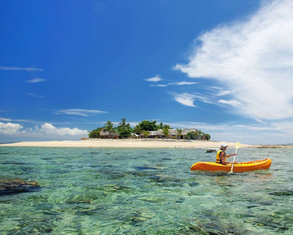 Une jeune femme en kayak près de South Sea island, dans l'archipel des Mamanuca aux Fidji Une jeune femme en kayak près de South Sea island, dans l'archipel des Mamanuca aux Fidji